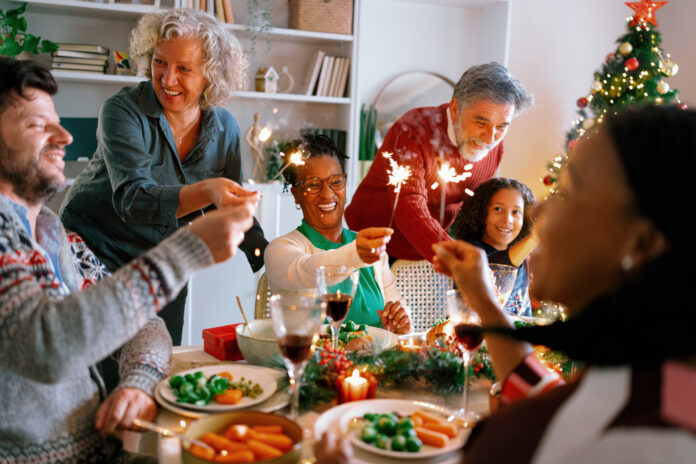 Multigenerational family holding sparklers and singing together, full of festive joy and energy.